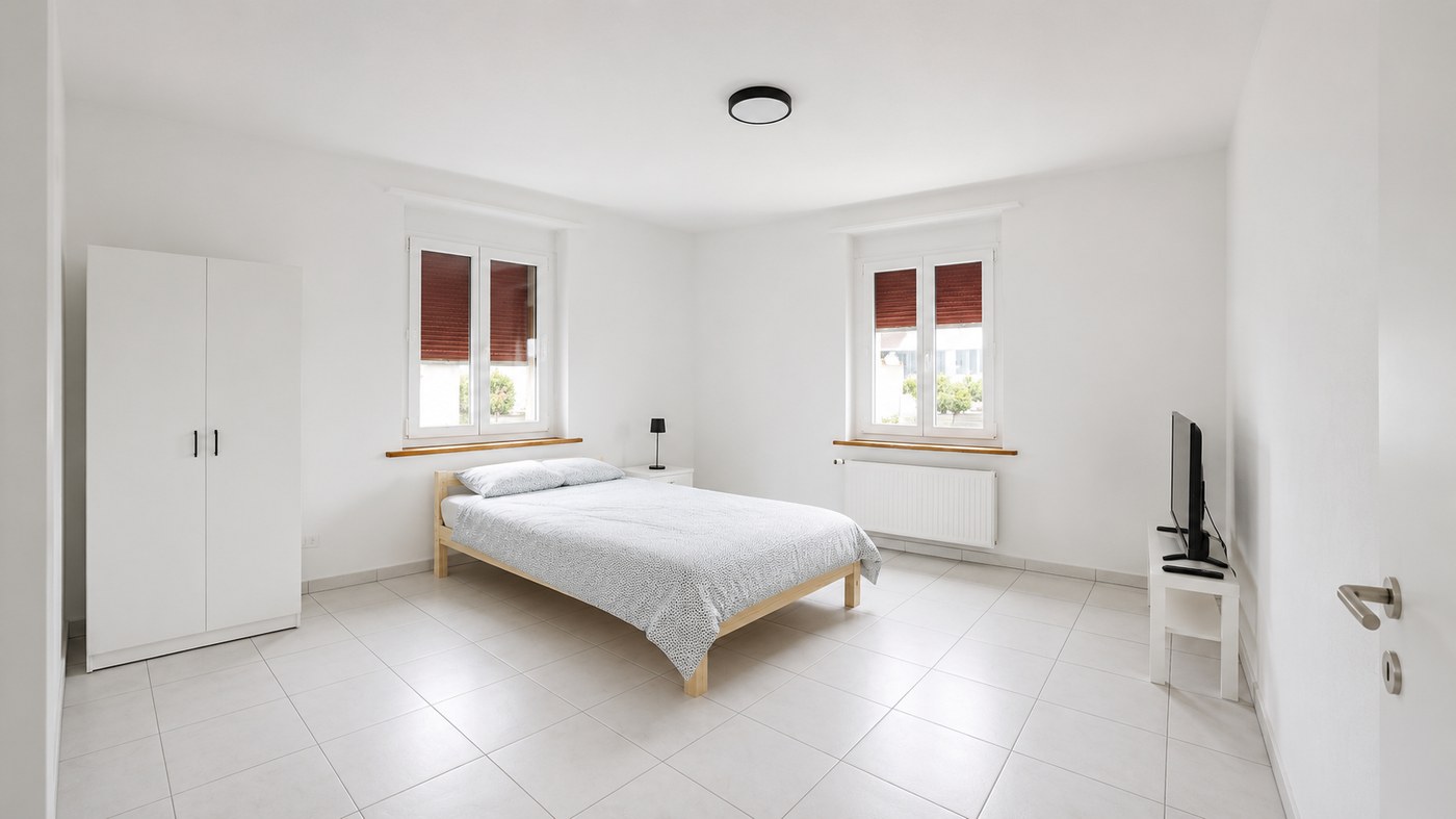 Helles möbliertes Zimmer mit Bett, Schrank und TV im Dream WorkPoint Grenchen